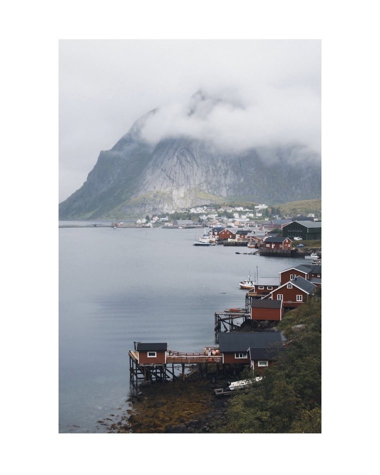 Red cabins on stilts below a cloud covered mountain, Lofoten